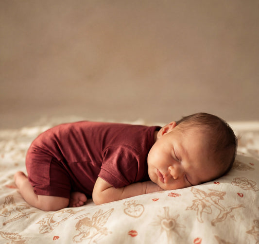 Newborn baby sleeping on a patterned blanket with a neutral background