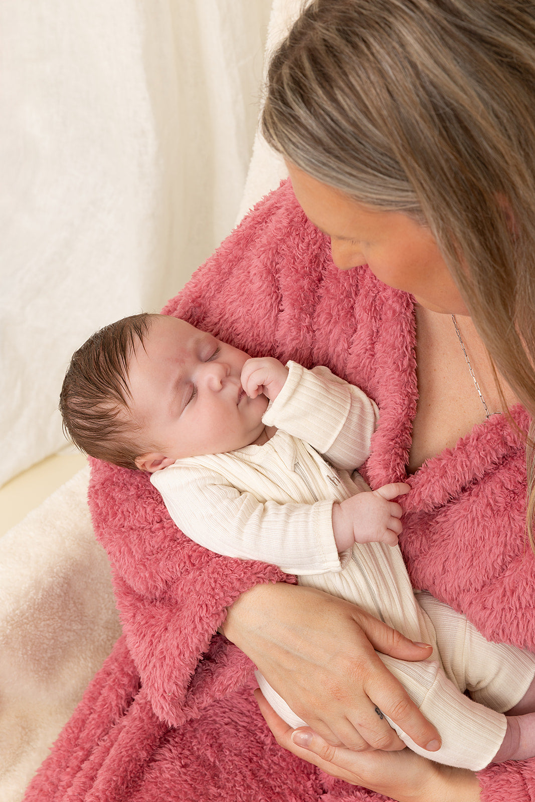 Woman holding a baby wrapped in a pink blanket