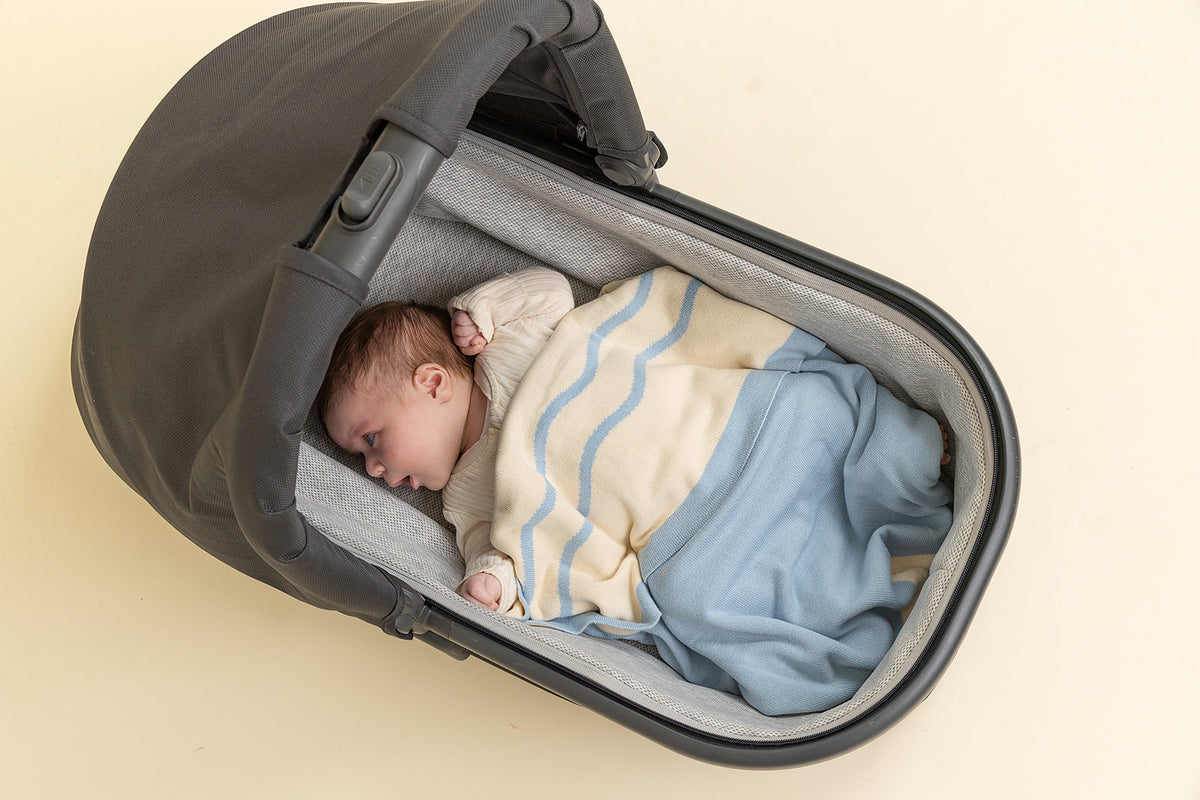 Baby sleeping in a black baby carrier with a beige background