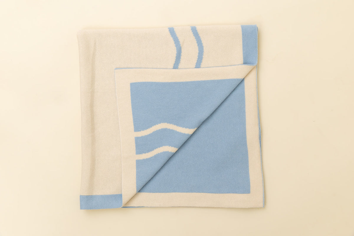 Folded blanket with blue and beige pattern on a beige background