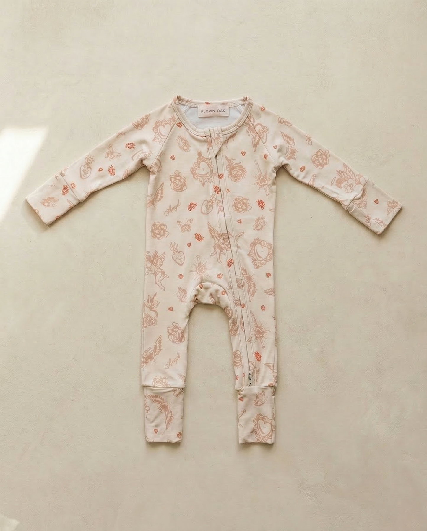 Floral-patterned baby onesie on a beige surface