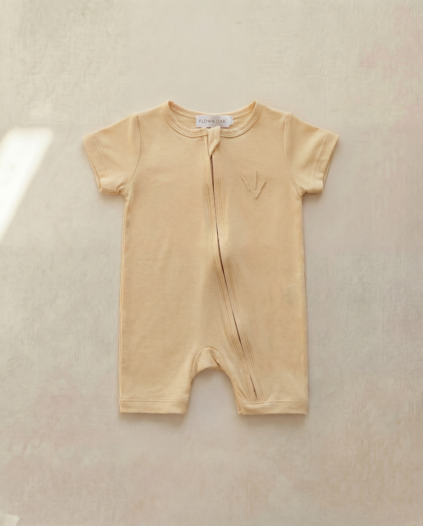 Beige baby romper on a light beige background