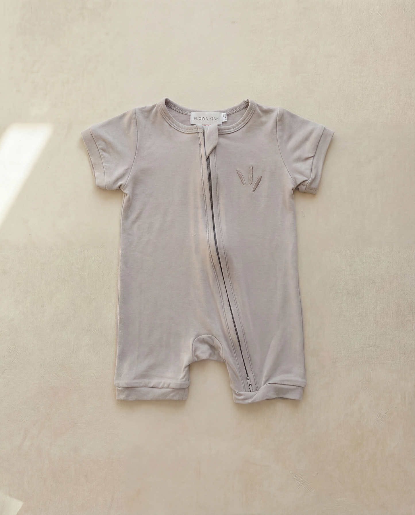Baby romper with zipper on a beige background