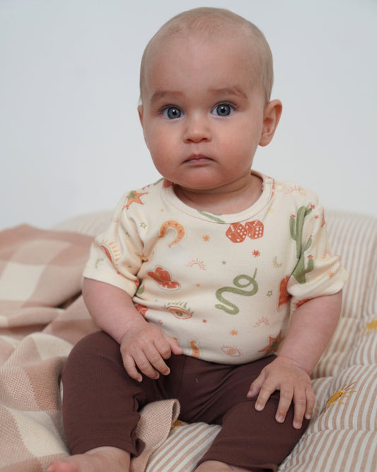 Baby wearing a shirt with snake designs on a striped blanket