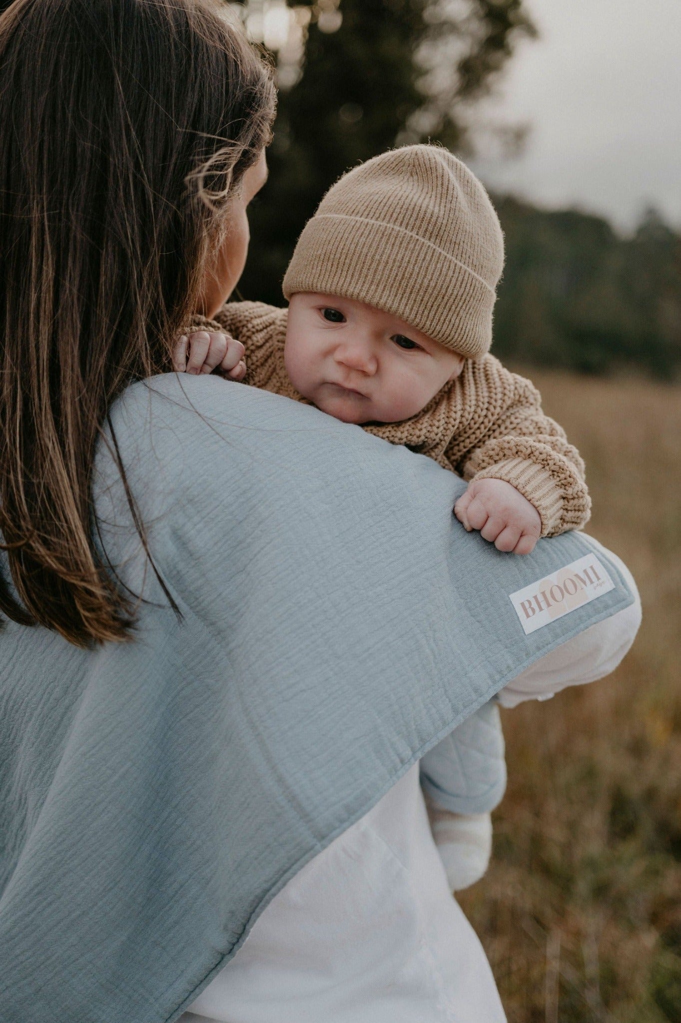 Mother burping her baby with a tie up burp cloth and nursing cover