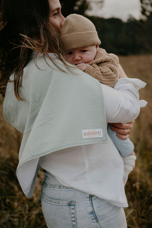 New mother burping her baby boy with a tie up burp cloth and nursing cover
