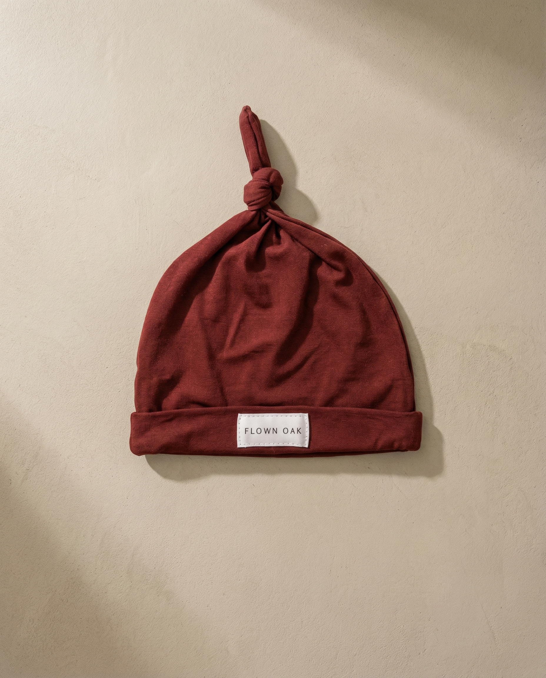 Red baby hat with a brand label on a beige background