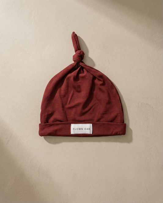 Red baby hat with a brand label on a beige background