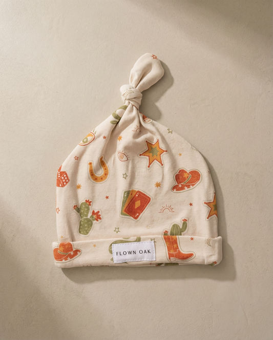 Baby hat with cowboy pattern on a beige background