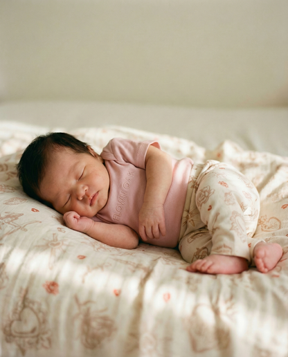 Newborn baby sleeping on a soft surface with a pink outfit