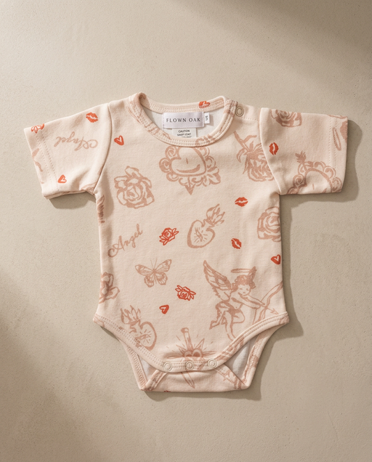 Baby onesie with floral and fairy pattern on a beige background