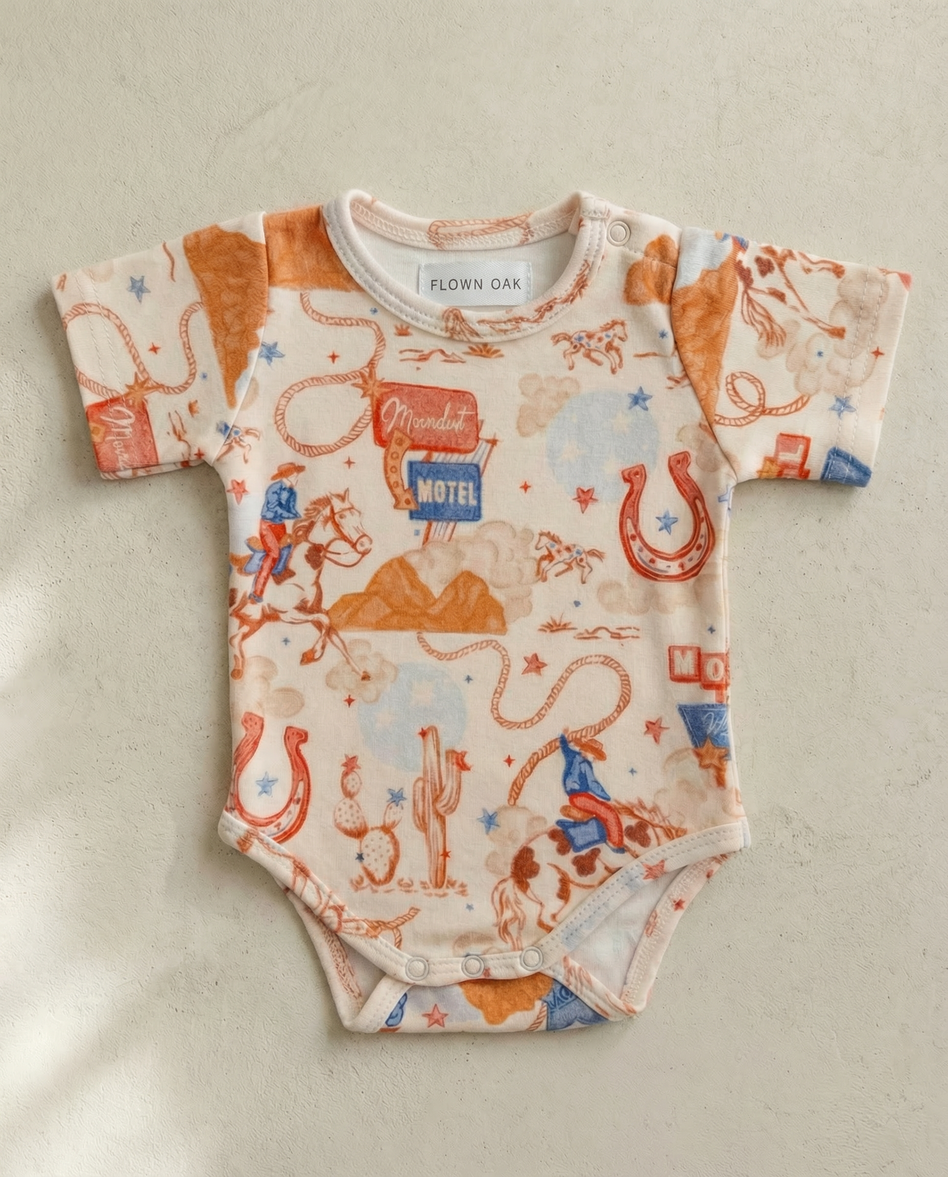 Baby onesie with vintage-style graphics on a beige background
