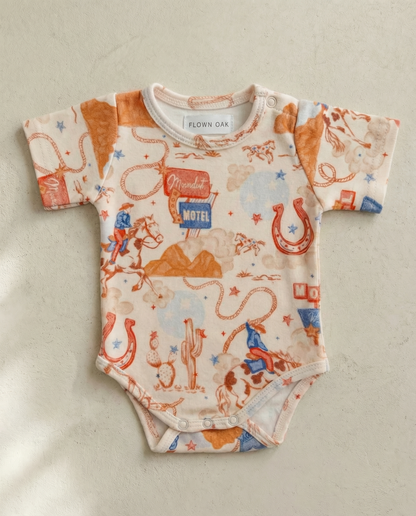 Baby onesie with vintage-style graphics on a beige background