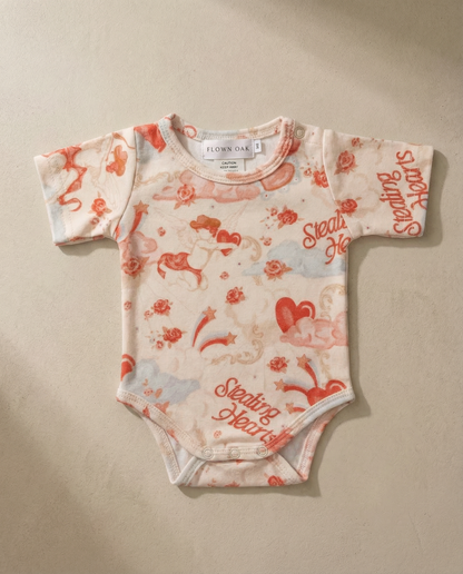 Baby onesie with red and white pattern on a beige background