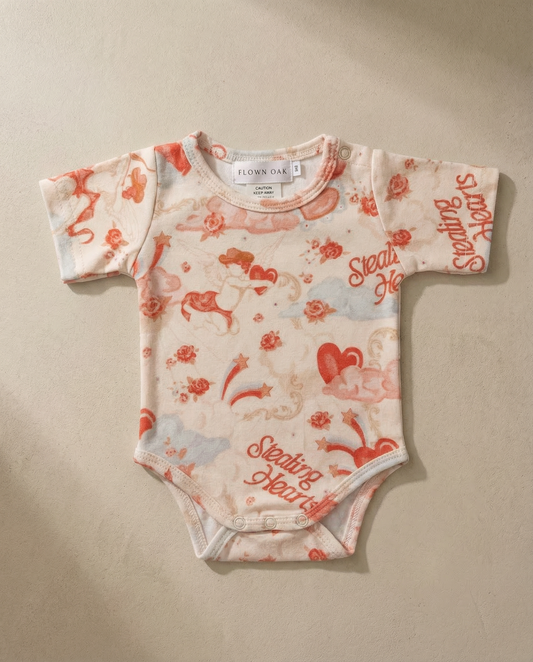 Baby onesie with red and white pattern on a beige background