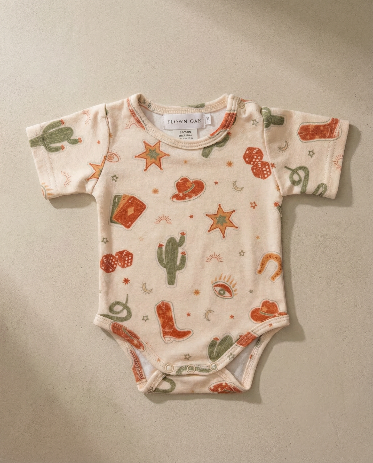 Baby onesie with cowboy pattern on a beige background