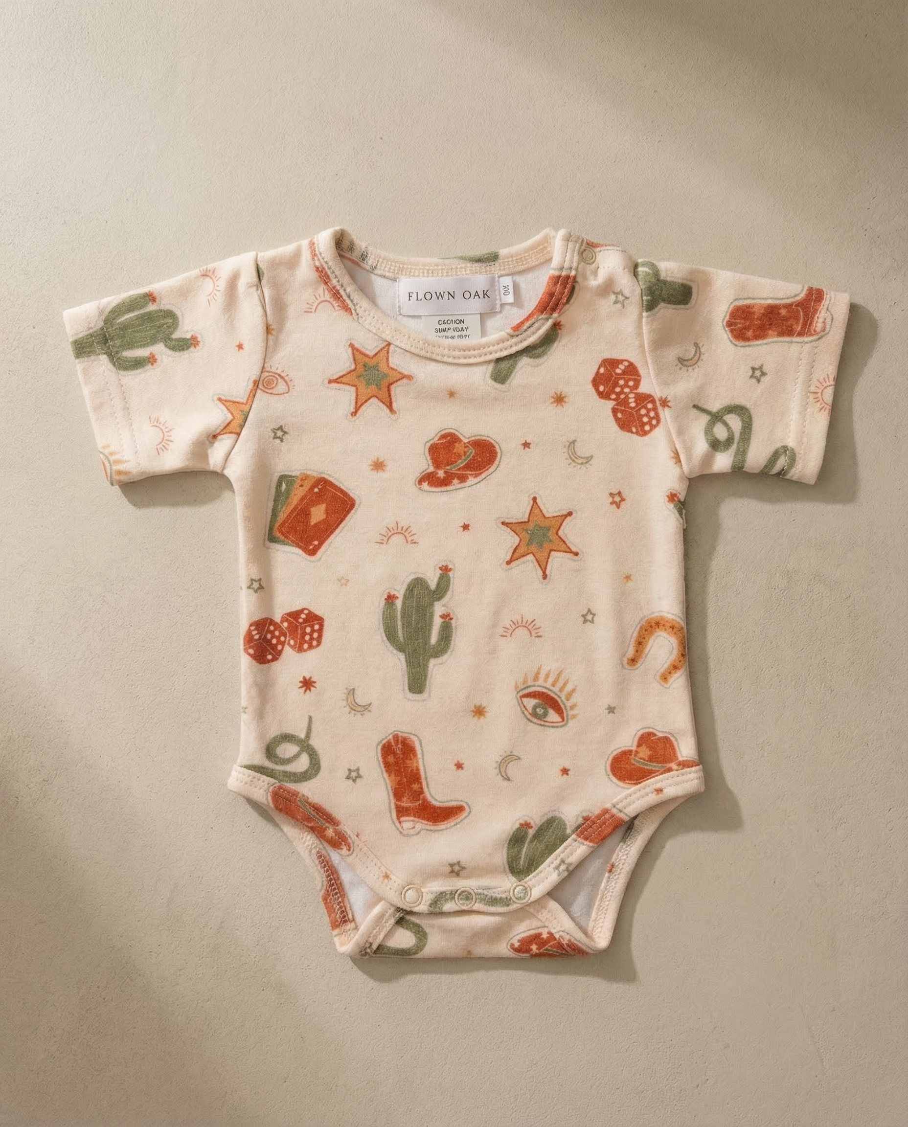 Baby onesie with cowboy pattern on a beige background