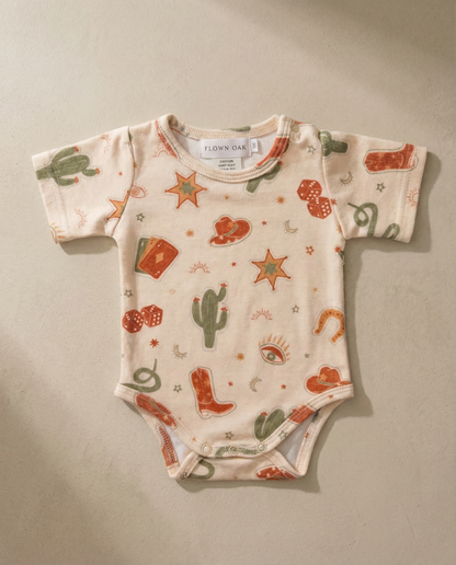 Baby onesie with cowboy pattern on a beige background