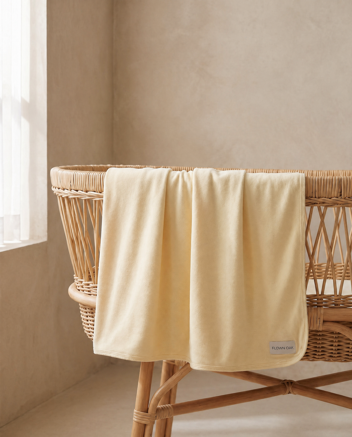 Yellow swaddle draped over a wicker bassinet in a softly lit room.