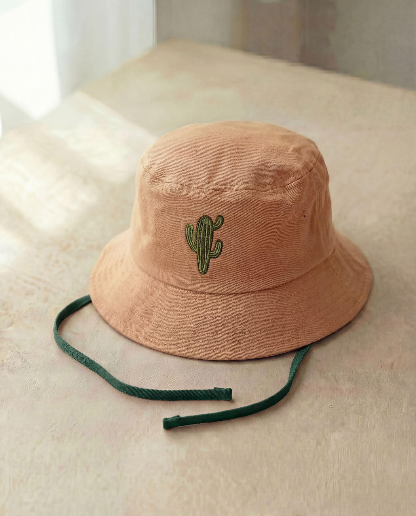 Beige bucket hat with a cactus embroidery on a light surface