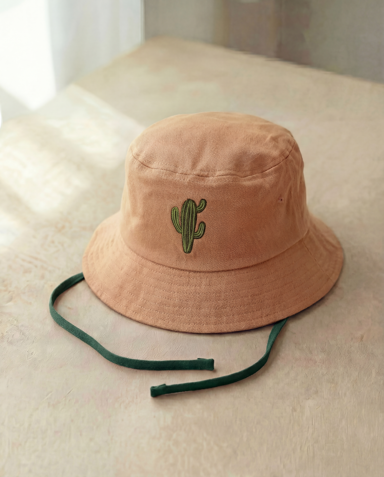 Beige bucket hat with a cactus embroidery on a light surface