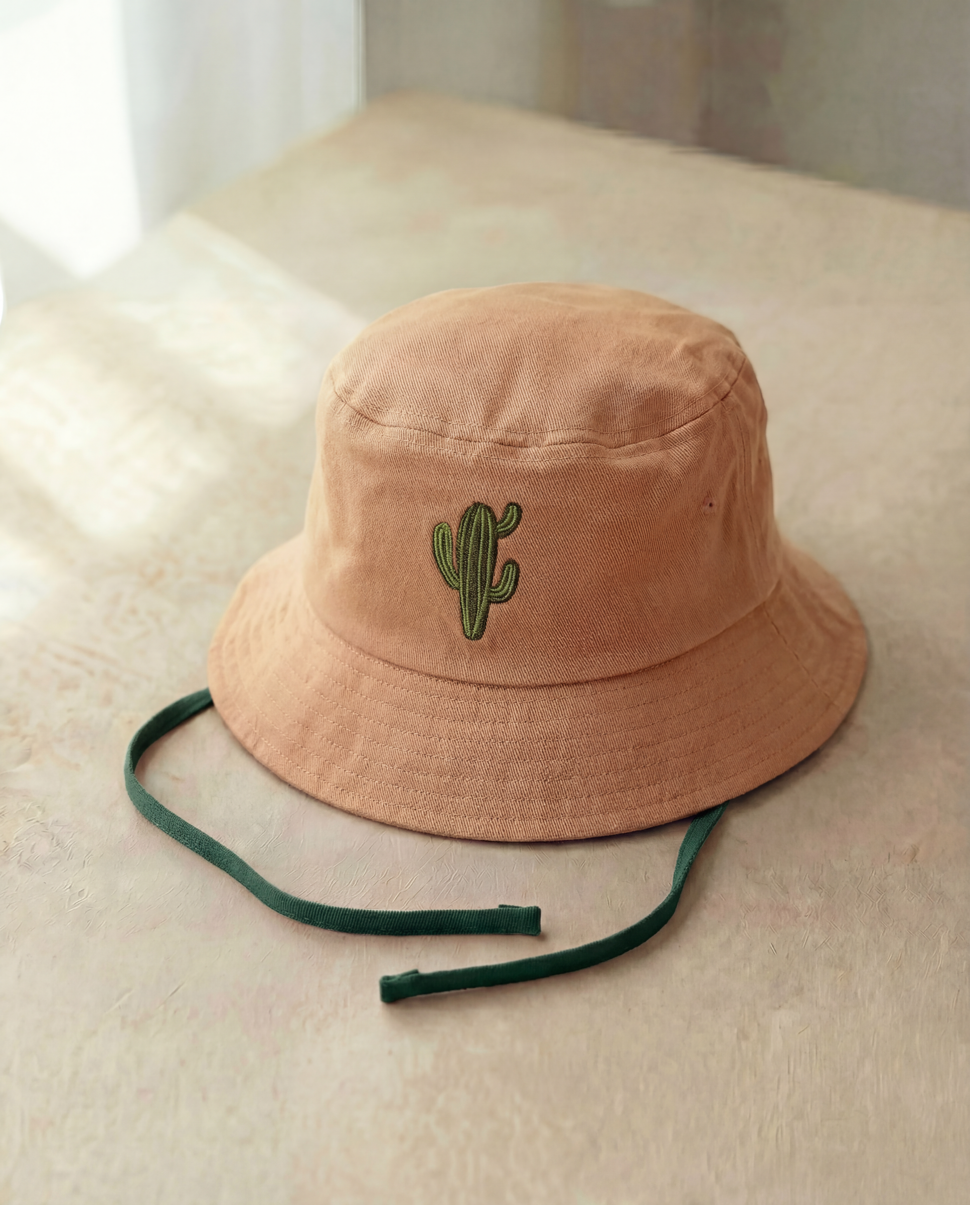 Beige bucket hat with a cactus embroidery on a light surface