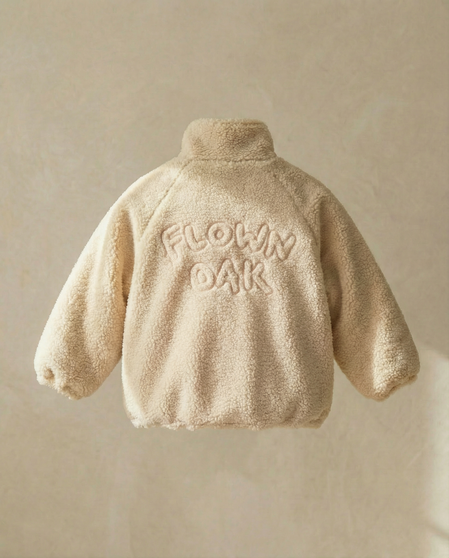 Beige fleece jacket with 'FLOWN OAK' text on a beige background