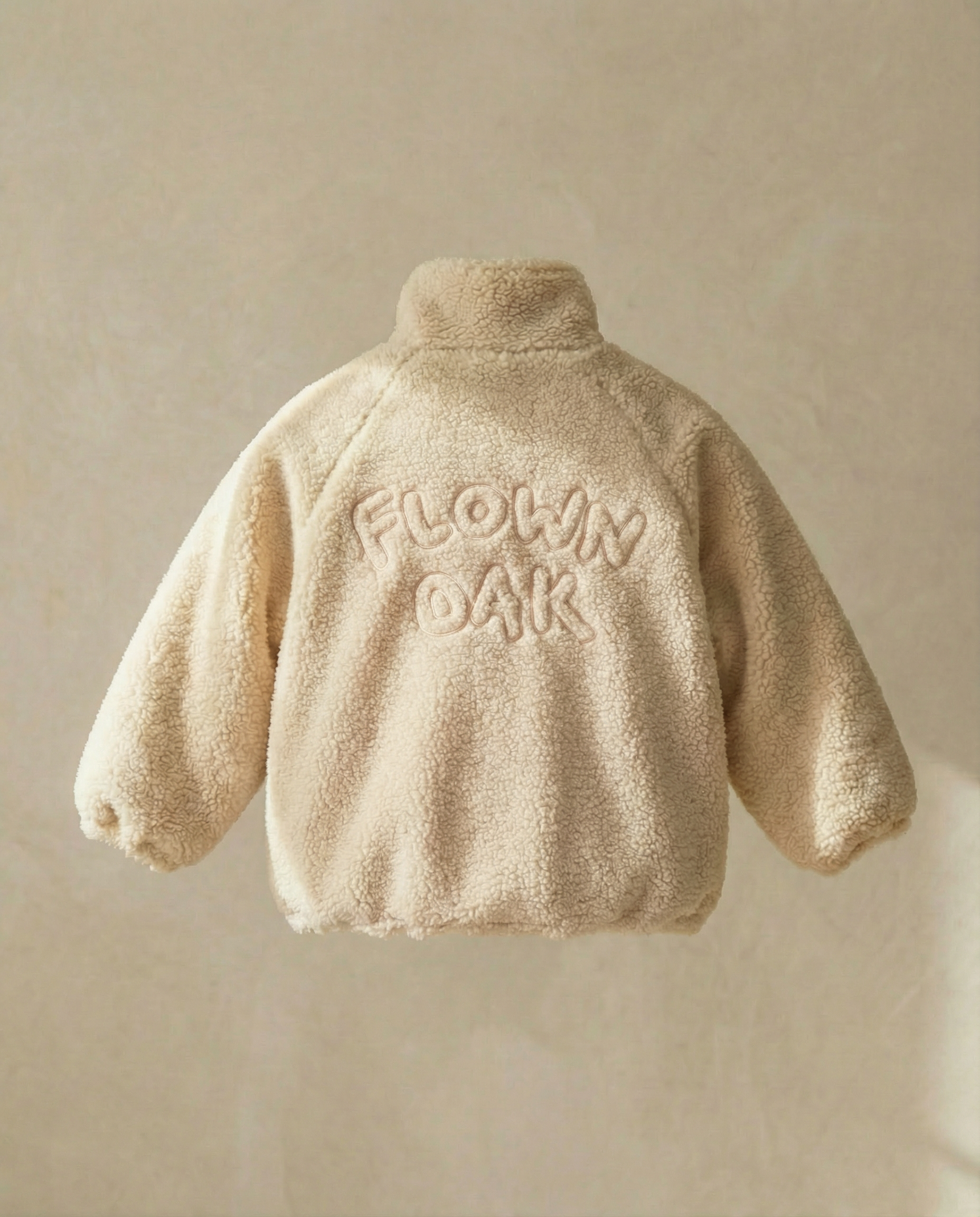 Beige fleece jacket with 'FLOWN OAK' text on a beige background