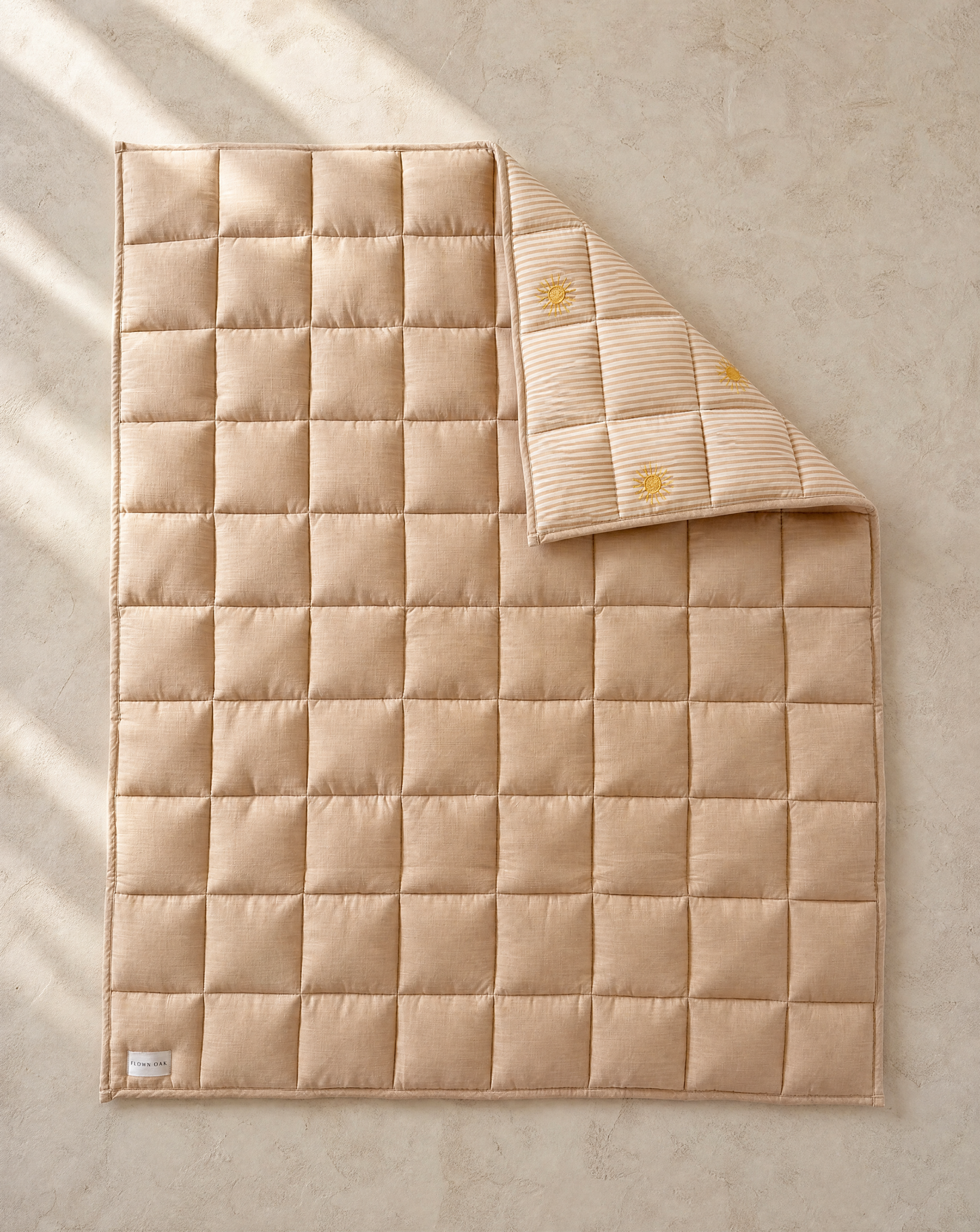 Beige quilted blanket on a textured beige surface