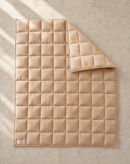 Beige quilted blanket on a textured beige surface