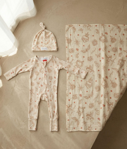 Baby outfit set with onesie, hat, and blanket featuring animal prints on a neutral background.