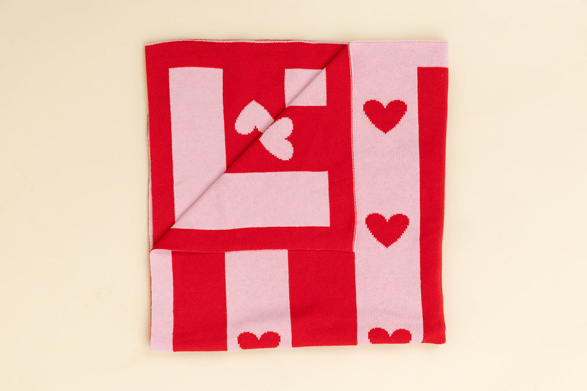 Red and pink blanket with heart patterns on a beige background