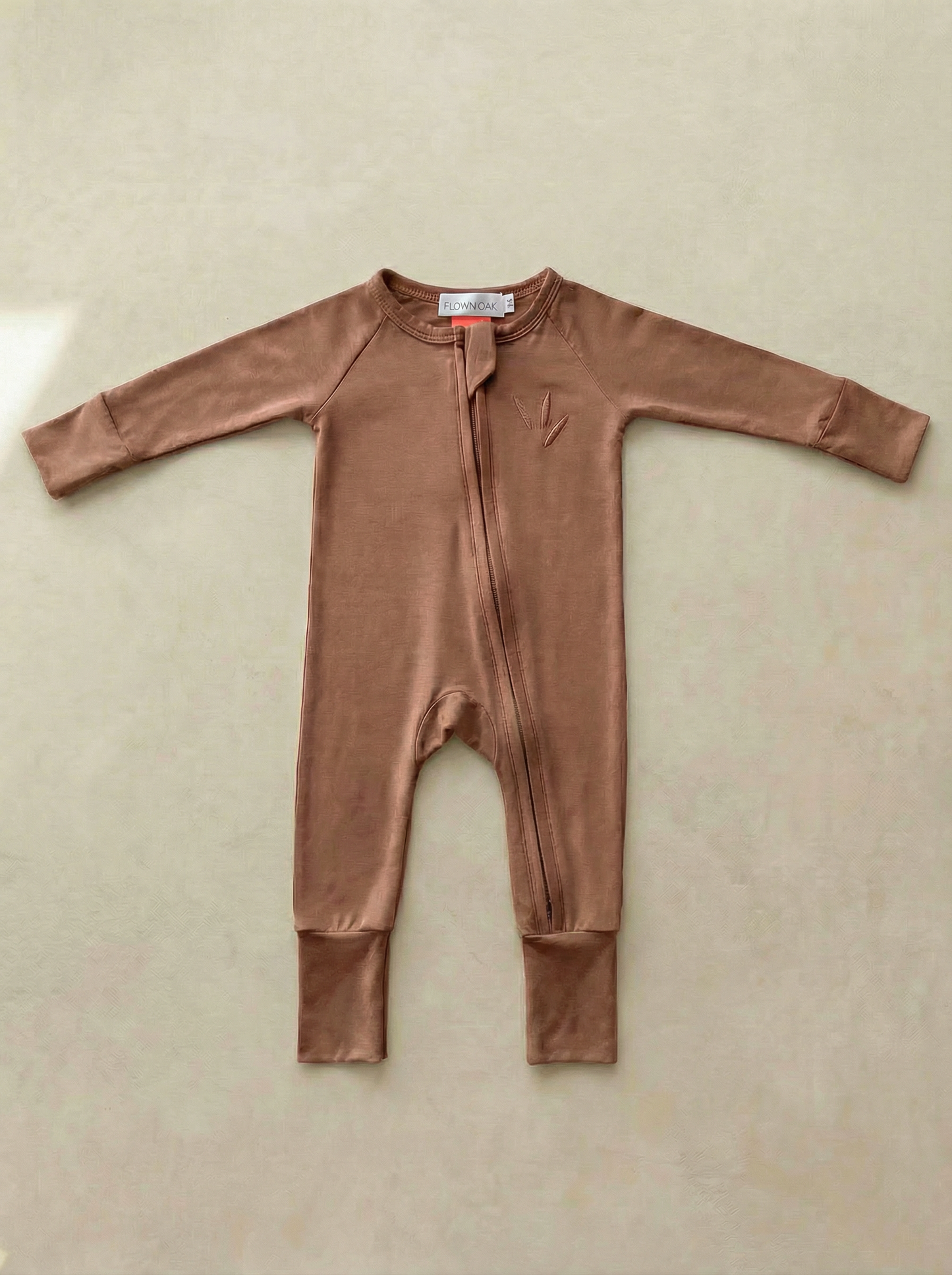 Brown baby onesie on a beige surface