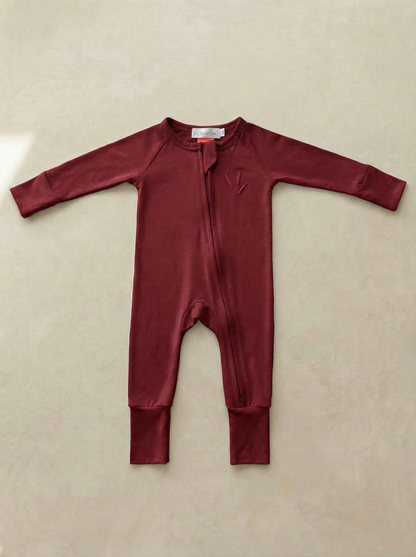 Maroon baby onesie on a beige background