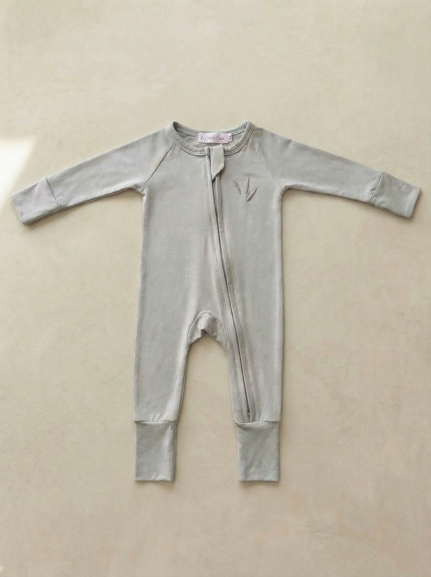 Light blue baby onesie on a beige background