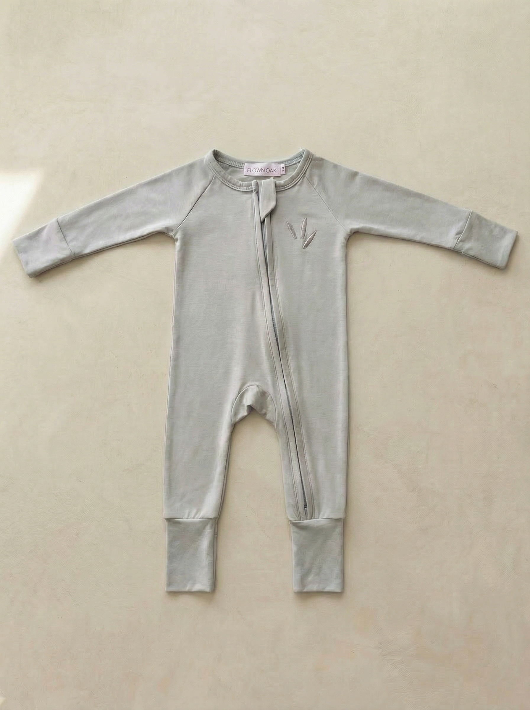 Light blue baby onesie on a beige background
