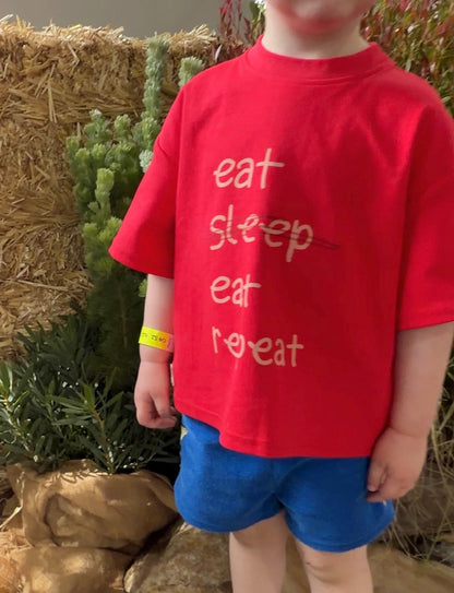 Boy in a red tshirt with Eat Eat Repeat on the front