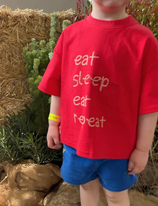 Boy in a red tshirt with Eat Eat Repeat on the front