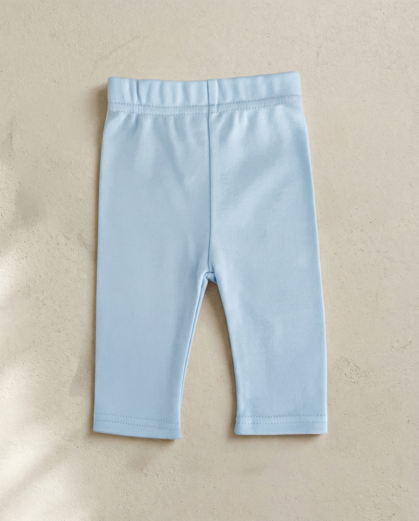Light blue baby leggings on a beige background