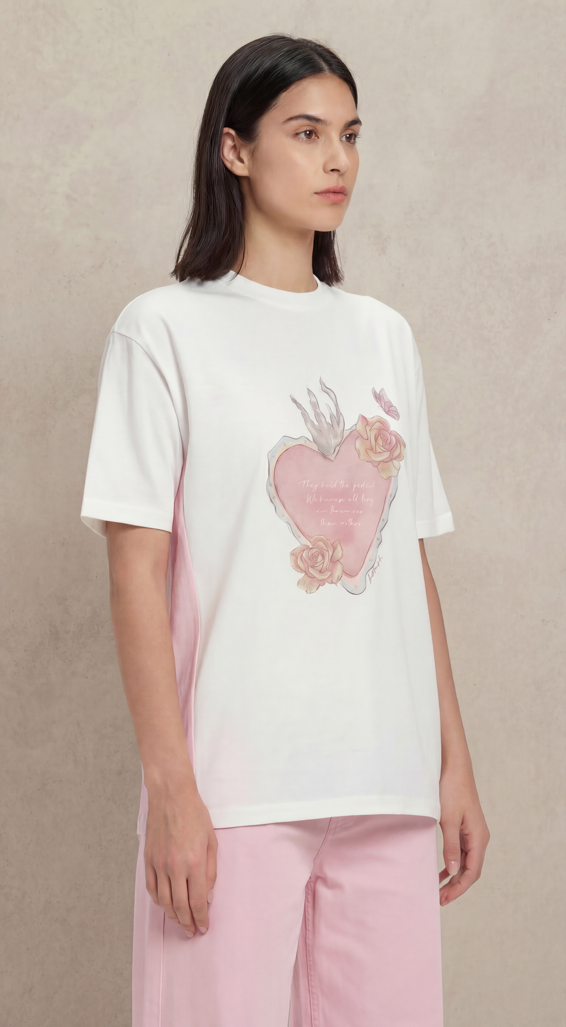 Woman wearing a white t-shirt with a pink heart design on a beige background