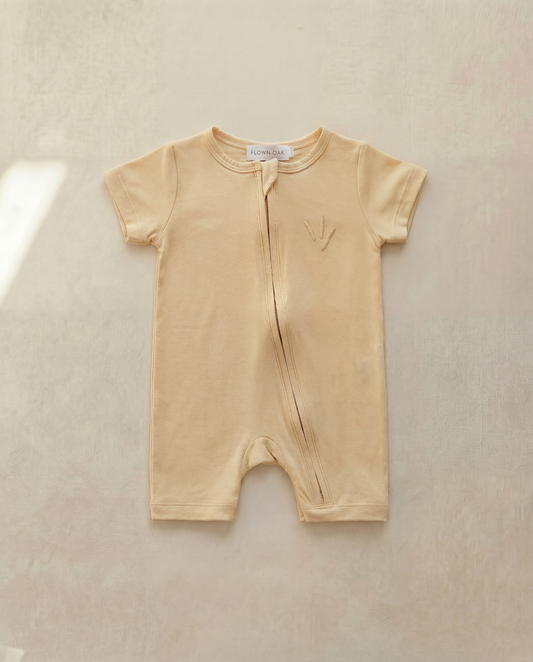 Beige baby romper on a light beige background