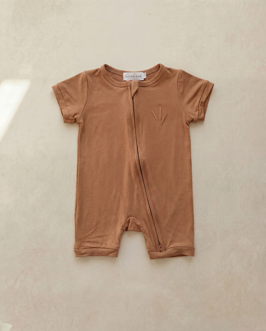Brown baby romper with a zipper on a beige background