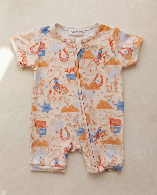 Baby romper with cowboy pattern on a beige surface