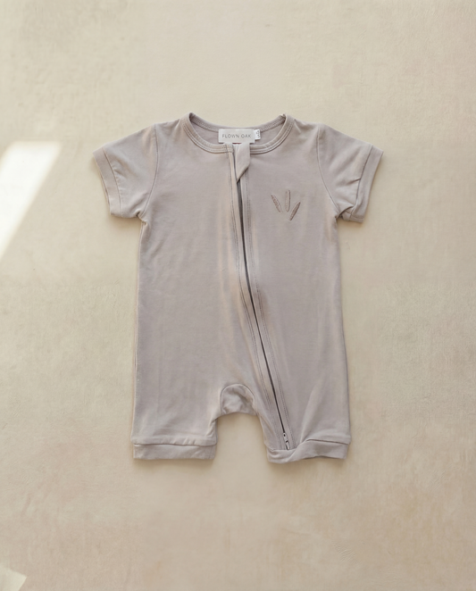 Baby romper with zipper on a beige background