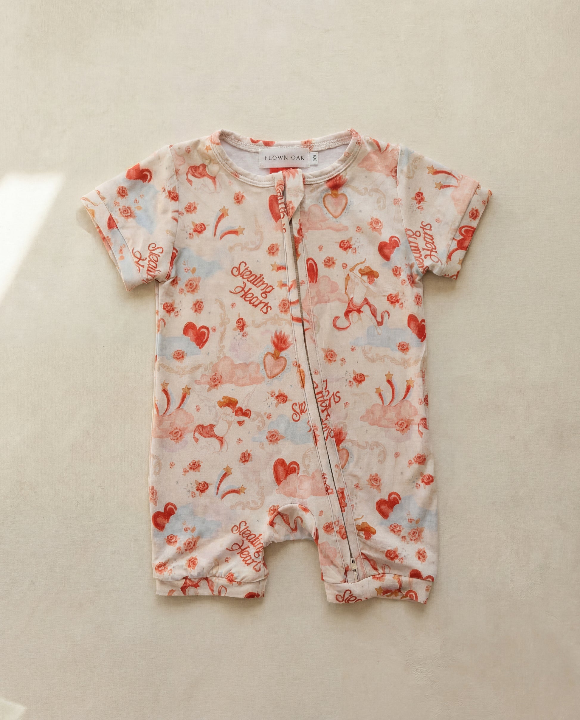 Baby romper with red and blue patterns on a beige surface
