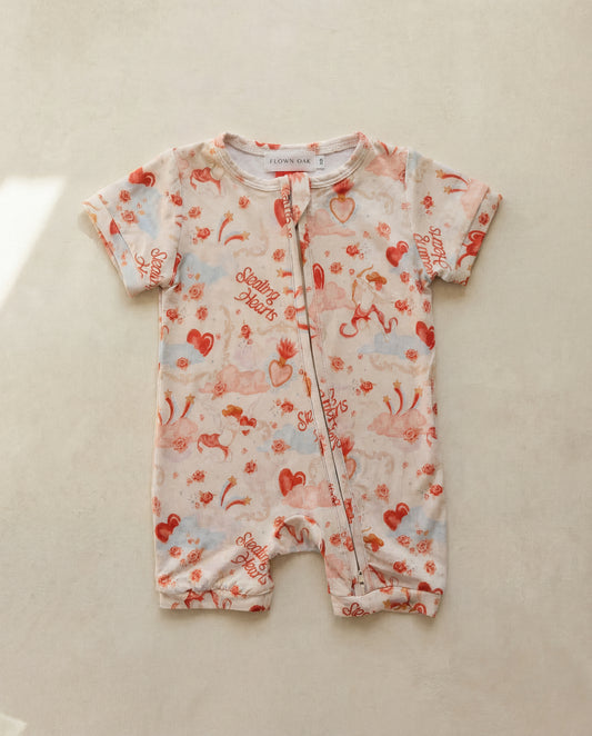 Baby romper with red and blue patterns on a beige surface
