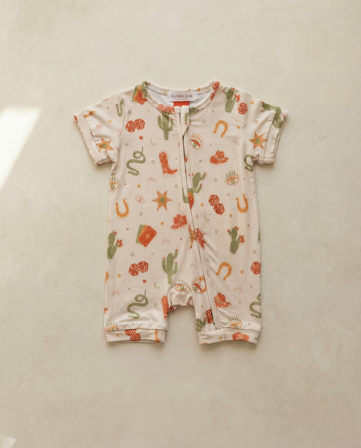 Baby onesie with cowboy-themed print on a light background