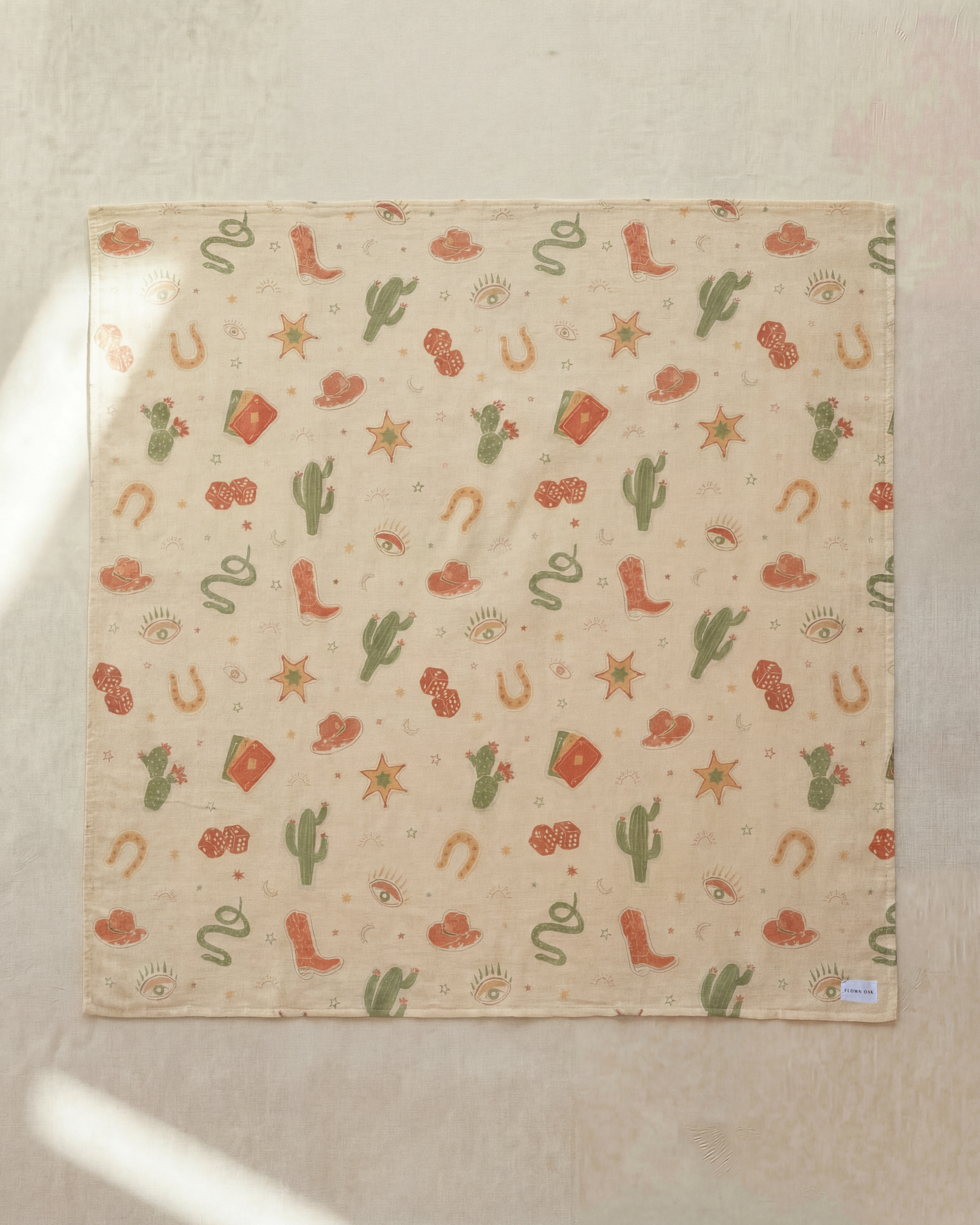 Patterned fabric with cacti, boots, and stars on a beige background