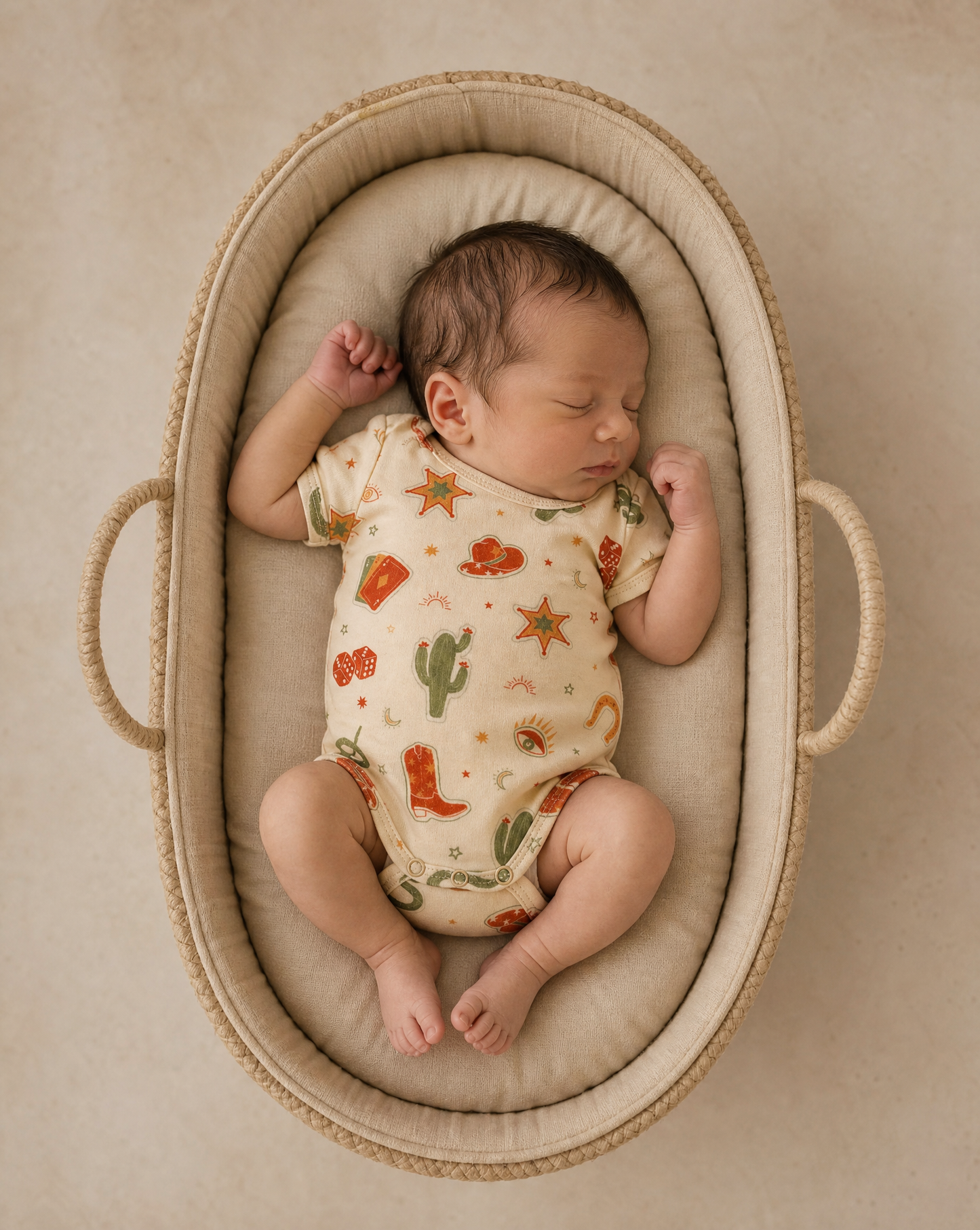 Newborn baby sleeping in a Moses basket with a patterned outfit.