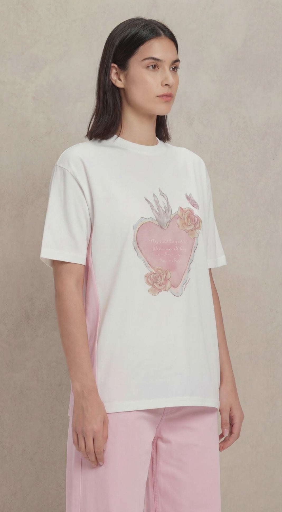 A video of a woman wearing a white tshirt with a heart image printed on the front